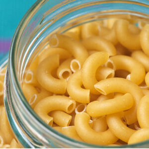 uncooked elbow macaroni stored in a glass jar