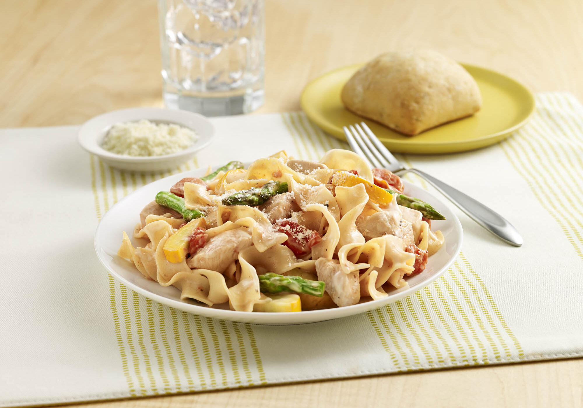 Egg noodles with chicken, asparagus, yellow squash, seasoned tomatoes, and Alfredo sauce