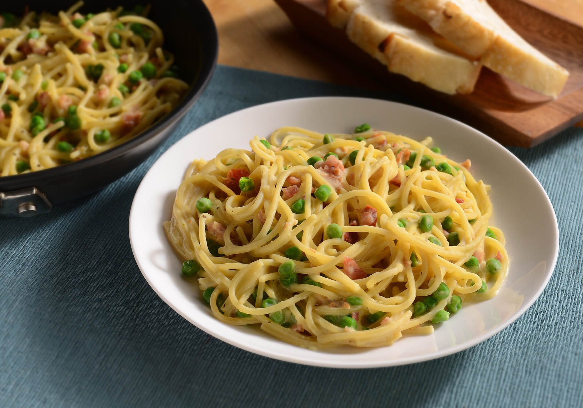 Linguine with crispy bacon and peas in a creamy sauce, topped with Parmesan cheese