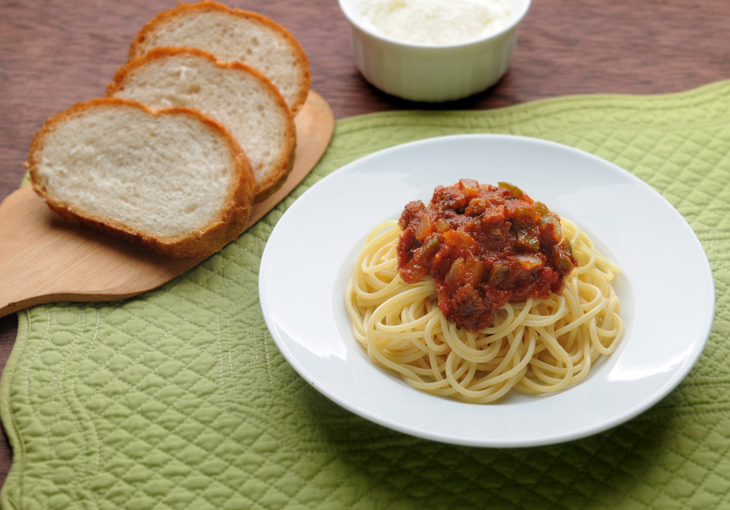 Spaghetti with Italian red sauce with onions and bell peppers and a side of bread